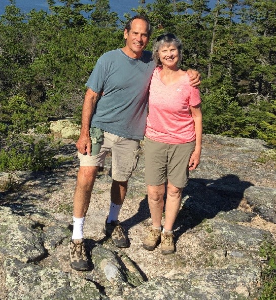 two people stand on a rock in a forested area