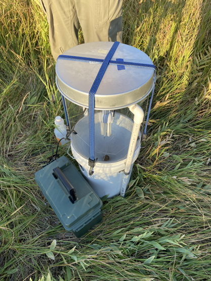 A cylindrical bucket placed on a grassy ground.