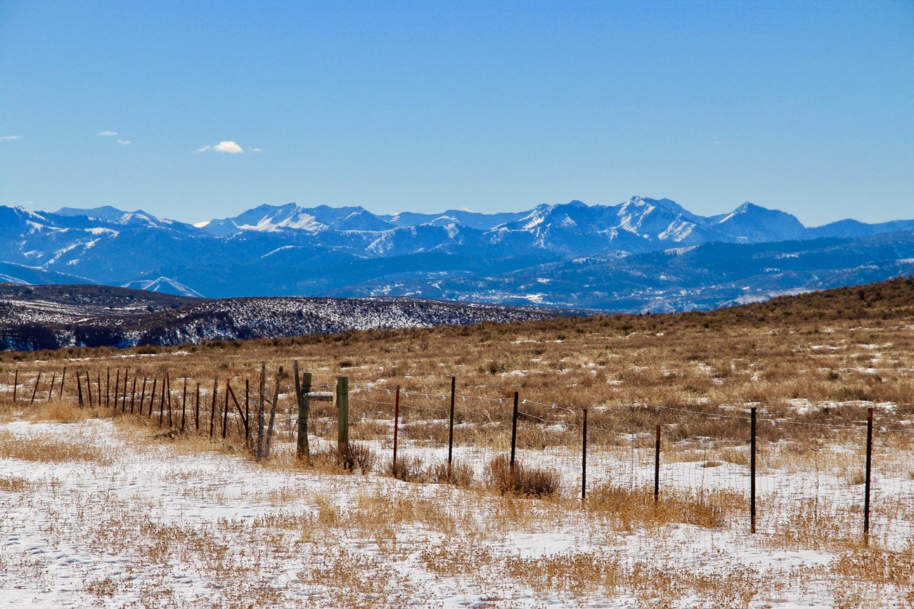 lt= Looking across a wintery landscape to distant snow-covered mountains.