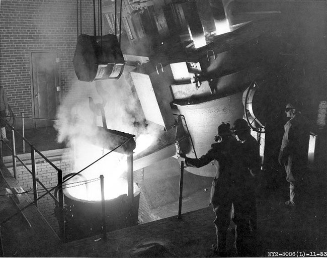 CNY-Foundry-7719 Workers in the foundry wearing protective gear and operating a large machine.