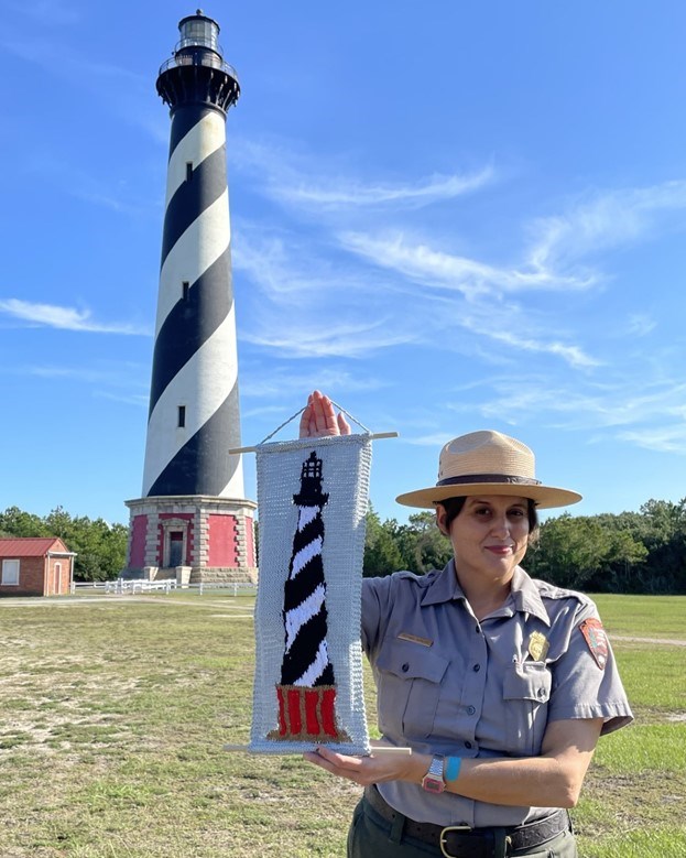 Ranger holds up lighthouse crochet pattern with lighthouse in background