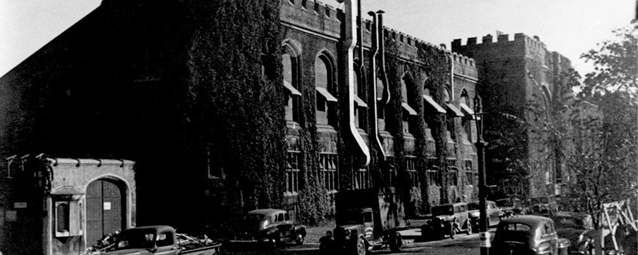 The Met Lab Black and white photo of a gothic-style university building with several cars on the street at the front.