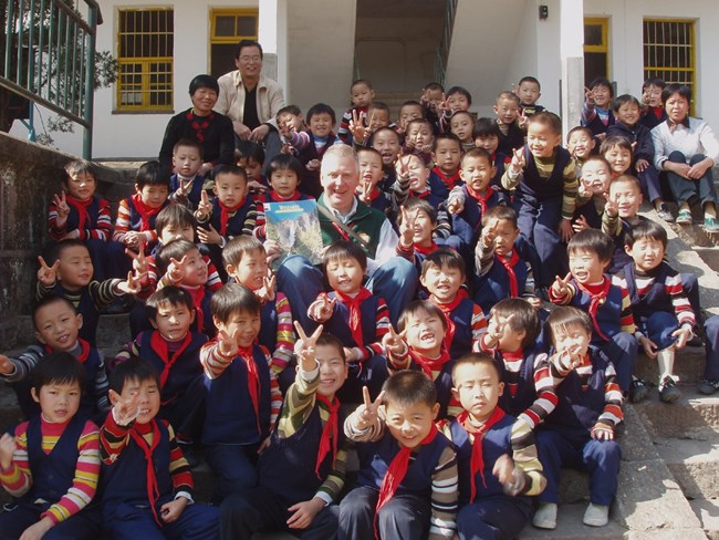 image of man holding a yosemite magazine, surrounded by a dozen kids from china