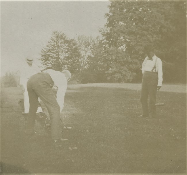 A black and white photograph of two men playing croquet.