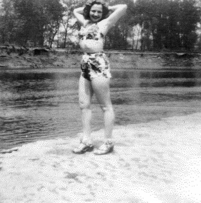 Cuyahoga River at Rockside-3 courtesy Josephine Moss - 05 A smiling young woman with wavy hair stands along a riverbank with her arms behind her head. She wears a patterned bikini and heels.