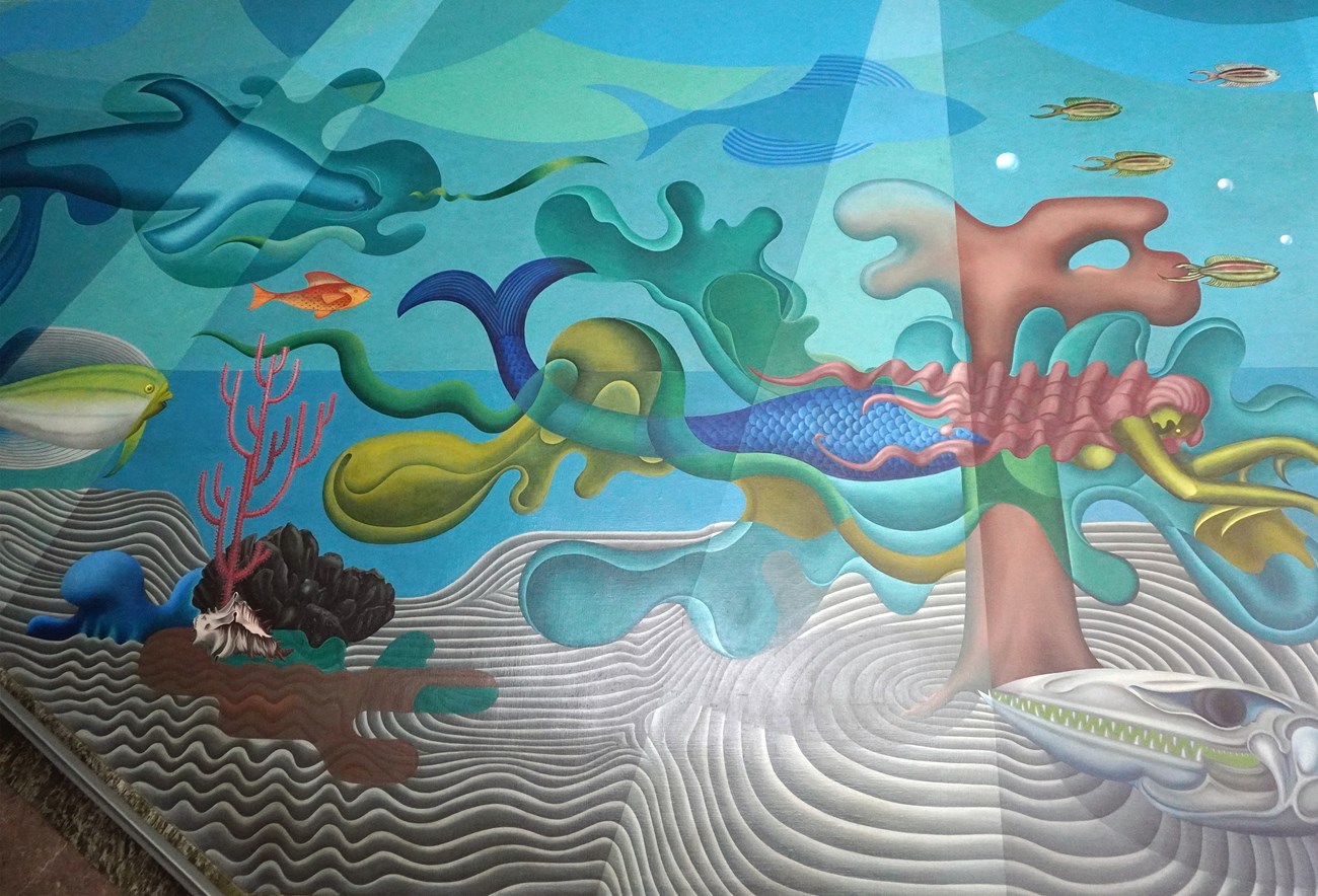 Stylized mural of an underwater scene uses bold blues, greens and pinks, showcasing fish and a mermaid.