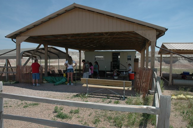 visitors gather under a canopy structure where fossil excavation takes place