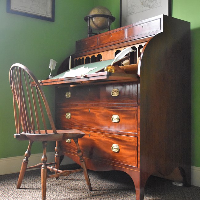 A federal-style desk of red-brown mahogany.
