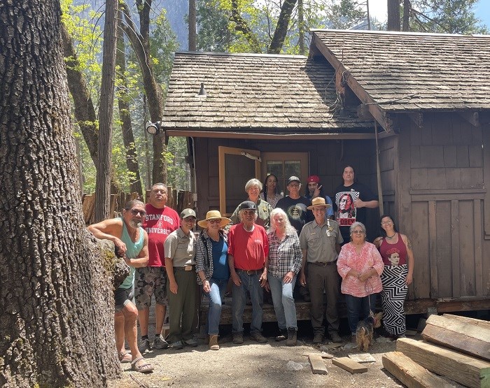 a group of people pose in front of wooden cabin