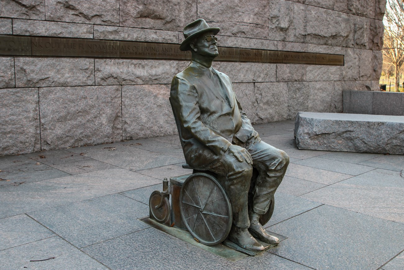 Statue of Franklin Delano Roosevelt seated in a wheelchair outdoors at the FDR Memorial.