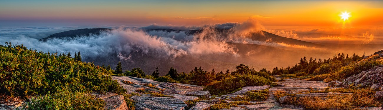 Landscape panorama of sunrise from a mountain punctuated with fog.