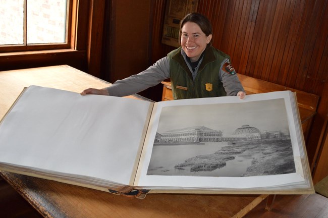 Two volumes of photographs from the 1893 World's Columbian Exposition Smiling park ranger holds open a very large book showing a historic photograph from the 1893 World's Columbian Exposition.