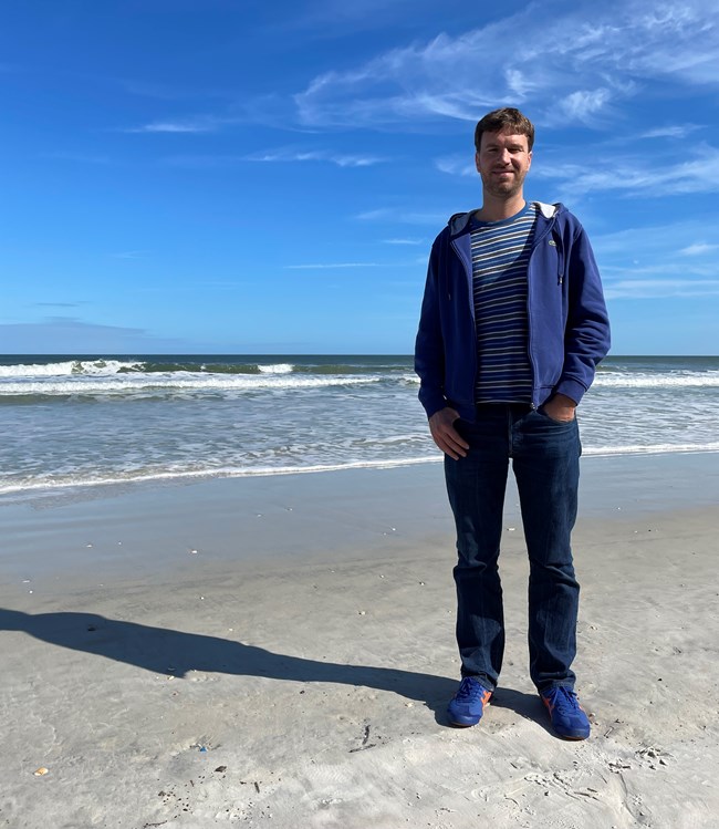 Artist in resident Felix on the beach with ocean and sky.