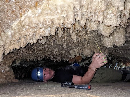 Person lying on back in small cave passage