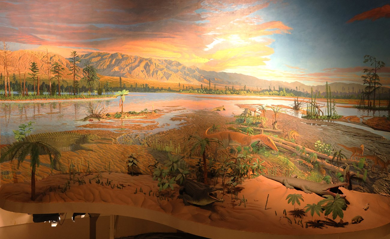 Photo of a diorama with wetlands, plants, and prehistoric animals.