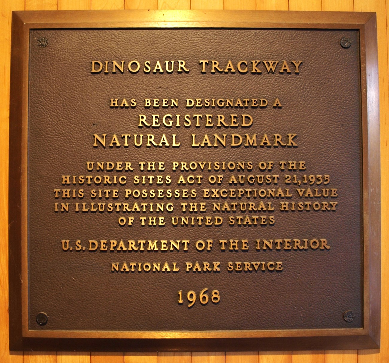 Photo of a metal plaque commemorating Dinosaur Trackway NNL designation in 1968.