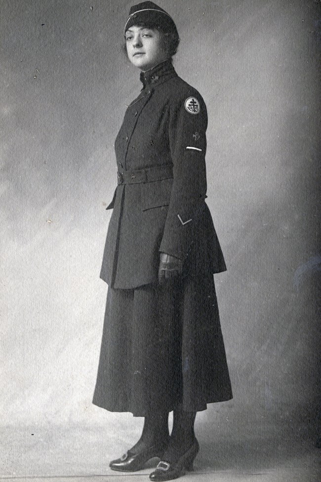 Portrait of woman in wool Army uniform consisting of formal coat, long skirt, leather gloves and garrison cap.