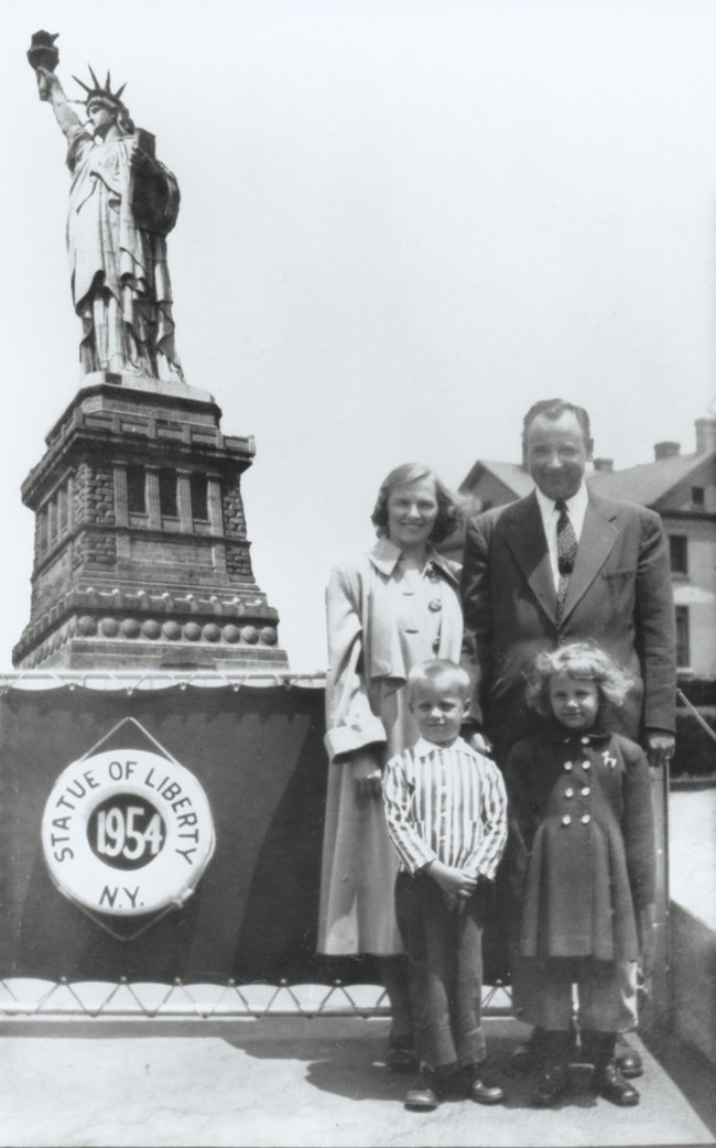 Two adults and two children pose in front of the Statue of Liberty.
