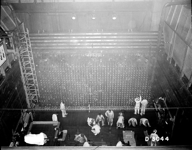 Black and white overhead view of machinery with people in lab coats working