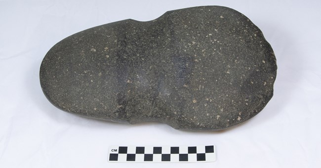 Full grooved axe Dark gray oval stone with concave band around the center.