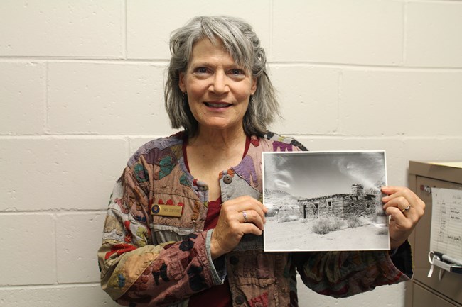 person poses holding a black and white photo of an stone building