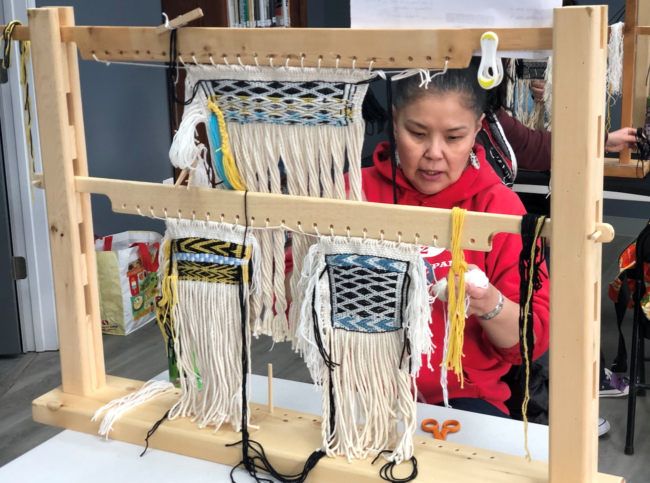 A weaver actively working on several Tlingit items