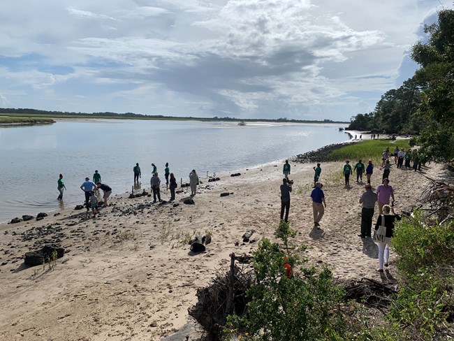 people stand on beach edge of river