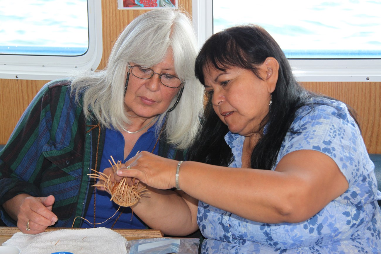 Two women inspect a tlingit woven item