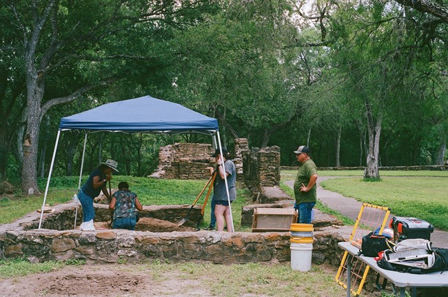 Group of people working on an archeological project under a tent