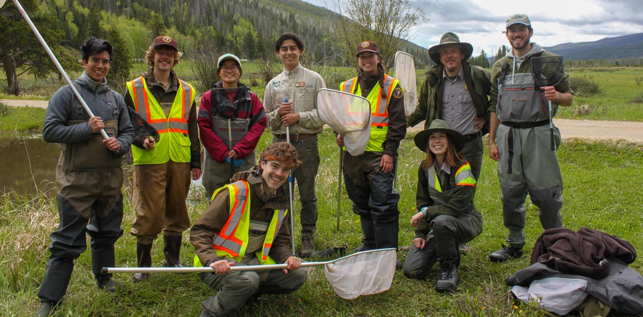 Nine interns pose for a photo in wetland collection uniforms.