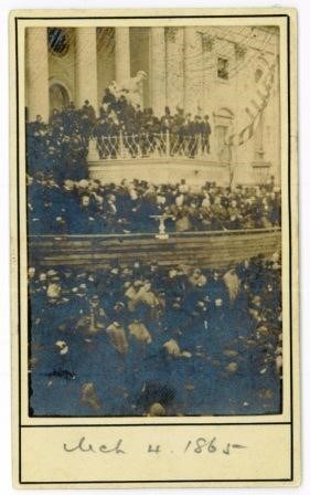 A faded image of a densely packed crowd gathered in raised tiers around a building. The date is hand-written at the bottom, March 4, 1865.