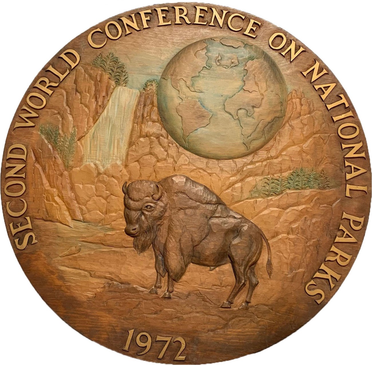 Round carved wooden plaque with bison and waterfall