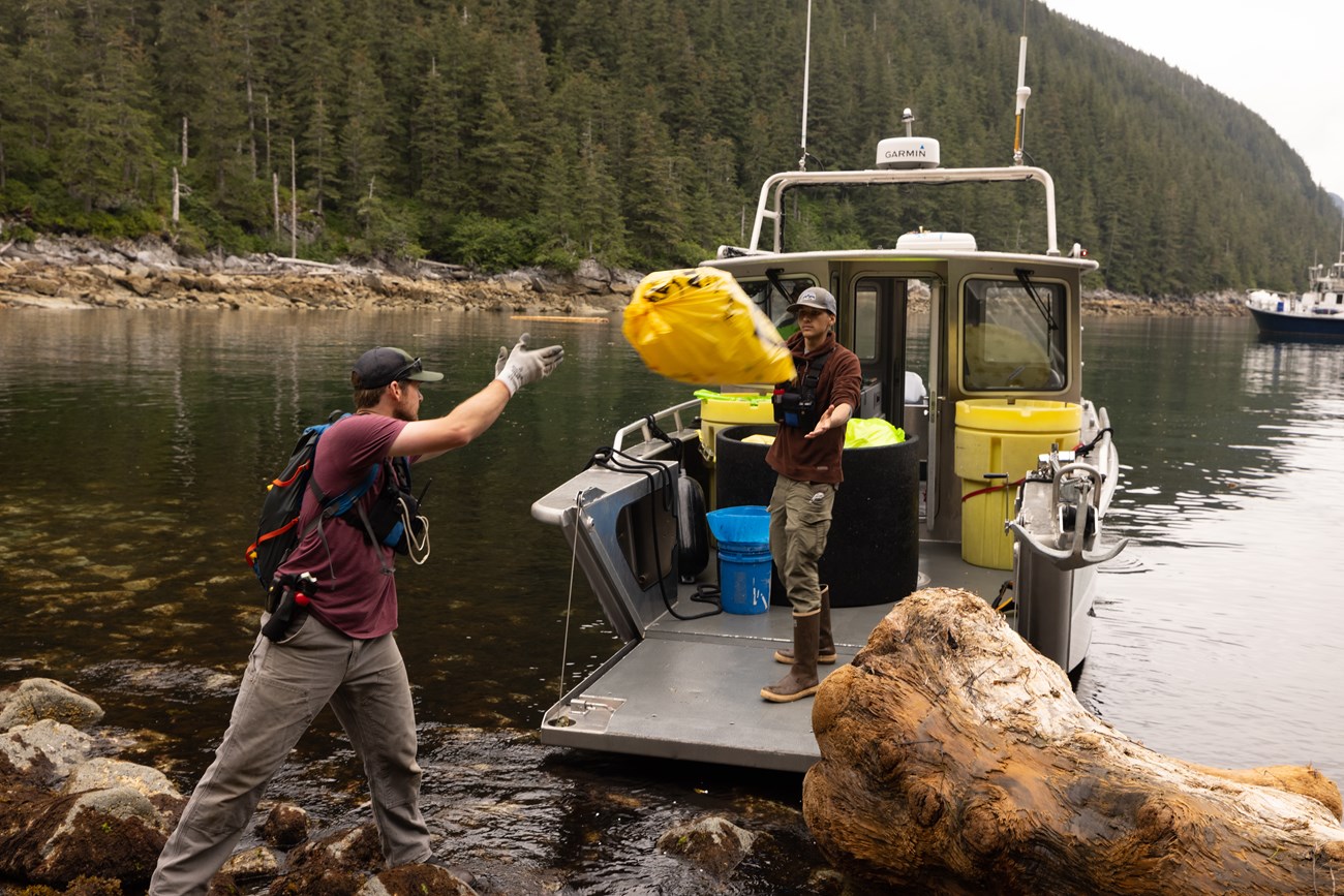 Volunteers load bags of marine debris onto a boat for disposal.