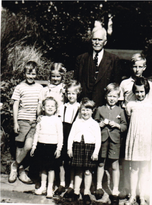 standing for a photo is a man with white hair and seven children