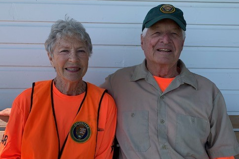 Bunny and Jim sitting on a bench wearing Volunteer neon orange.