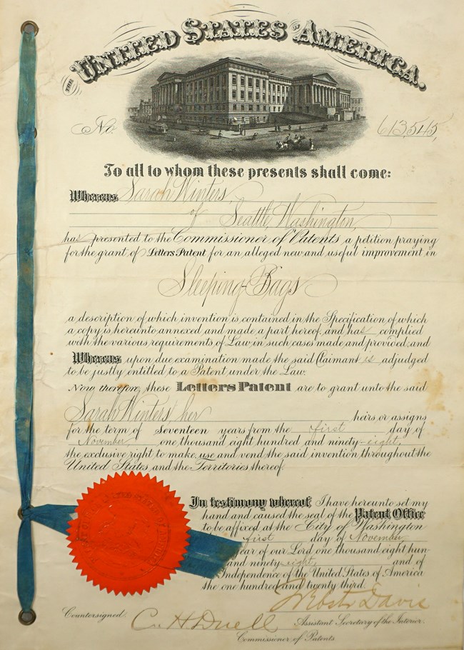 An old, yellowed patent document sits on top of blue fabric.