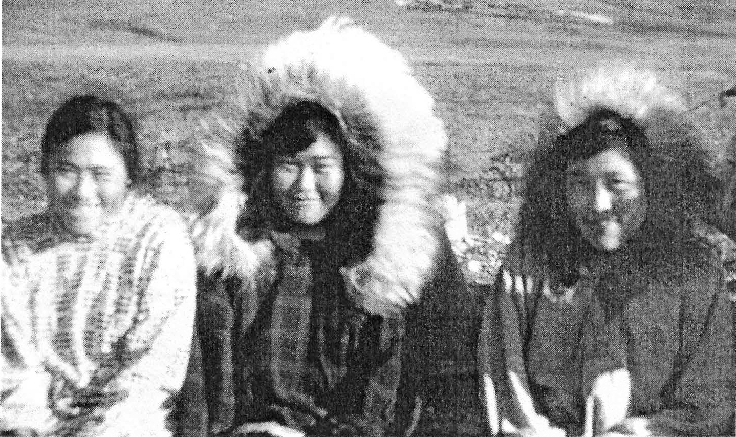 Black-and-white photograph of three young Alaska Native women sitting together