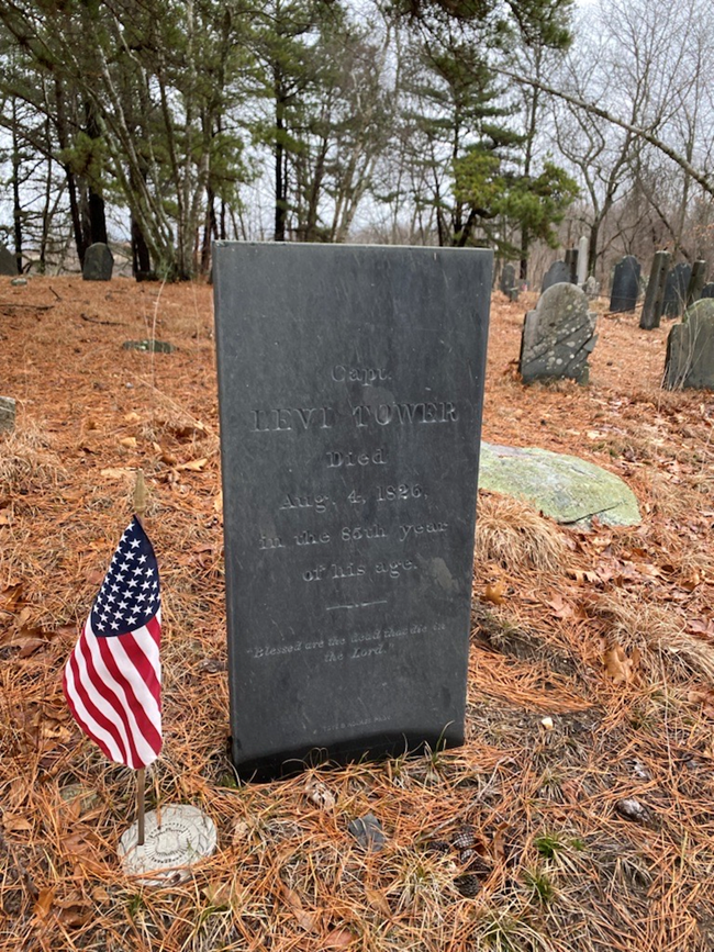 A gravestone on a hill with leaves