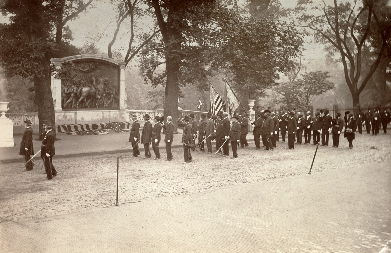 Veterans of the Massachusetts 54th Regiment standing in formation in front of the Shaw 54th Massachusetts Regiment Memorial.