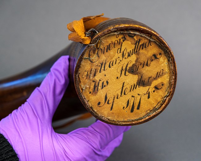 The open end of the powder horn with a wooden stopper and Willard Buttrick's name written