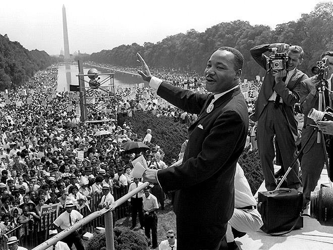 Dr. Martin Luther King, Jr. standing on a stage giving a speech to a huge crowd gathered on the National Mall
