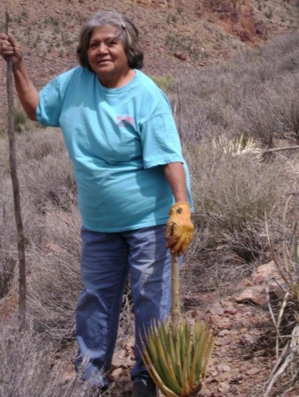 Middle aged woman standing next to agave plant with staff