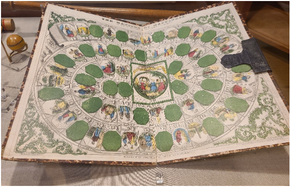 Mansion of Happiness board game with 66 spiraled rectangles showing christian figures and green designs inside a glass case.