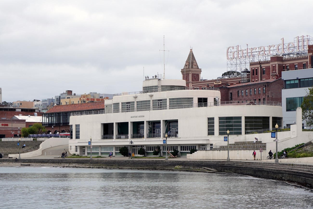 Four-story white building sits on the water's edge. Its curving lines and railings are reminiscent of an ocean liner.
