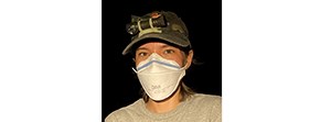 Molly Donlan A woman wearing an N95 mask and hat with headlamp looking at the camera