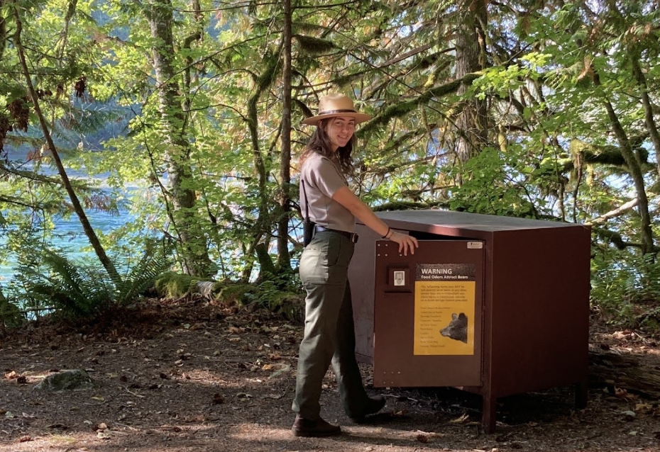 a ranger holds open the doors of a bear proof storage locker