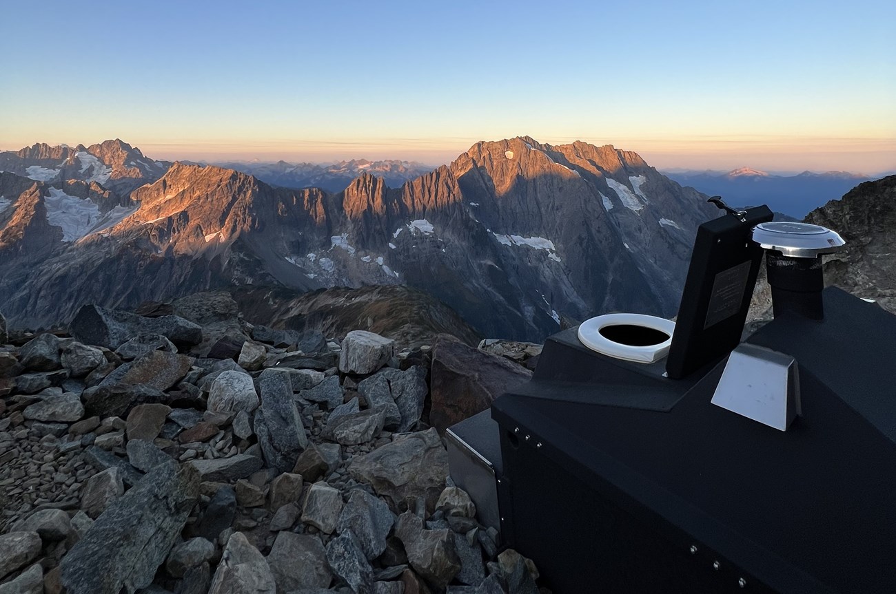 a composting toilet with a view of sharp peaked mountains at sunset