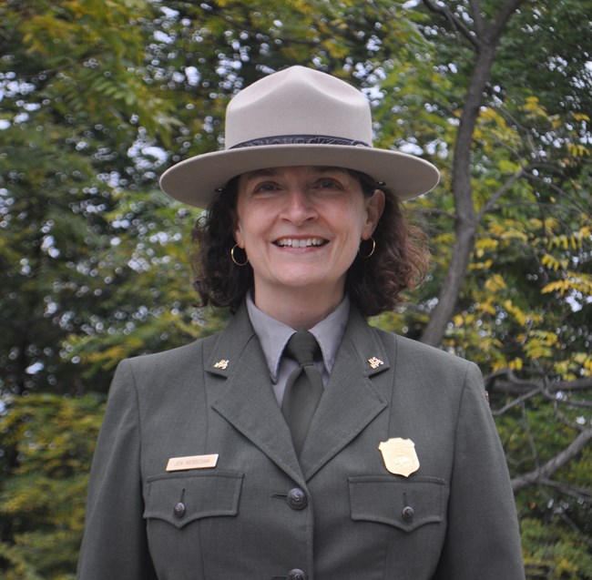a woman wearing the National Park Service uniform smiles at the camera