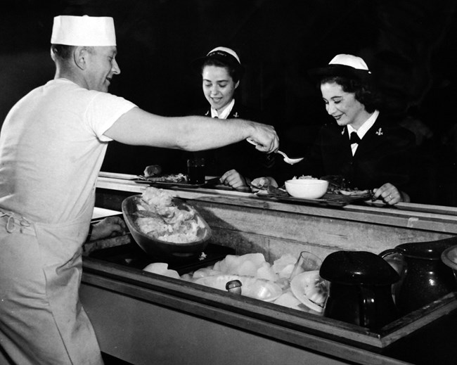 Naval Chow at Pasco WA Black and white photo of two women in uniform being served food by a man behind a counter