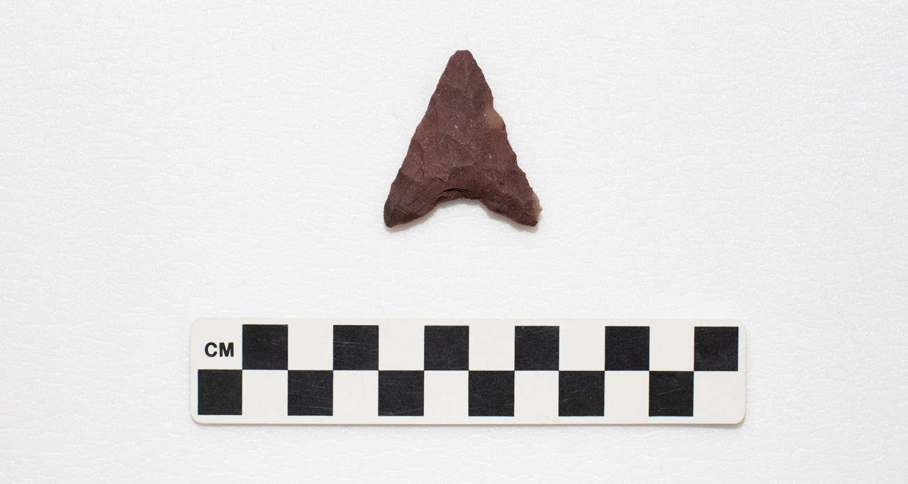 A triangular shape projectile point with concave shaped base.